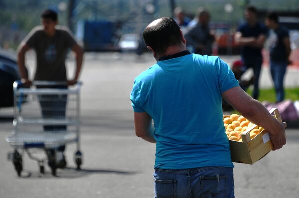Мужчина несет ящик с абрикосами в торговом комплексе Бухта в Москве - Sputnik Армения