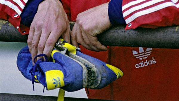 Советский спортсмен держит в руке  кроссовки Adidas - Sputnik Армения