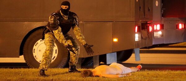 Сотрудник правоохранительных органов рядом с лежащим на земле протестующим во время столкновений после закрытия избирательных участков президентских выборов (9 августа 2020). Минск - Sputnik Արմենիա