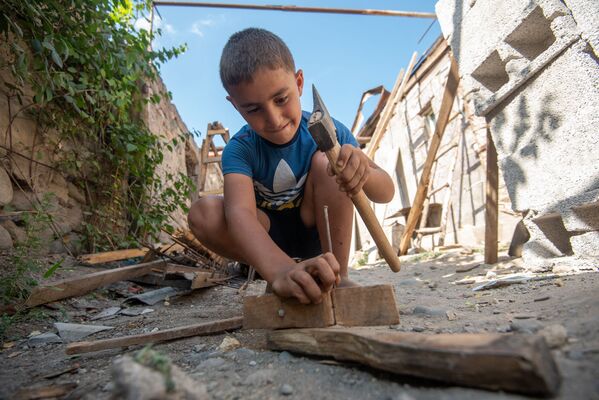 Мальчик играет с разобранными частями от старой крыши – он пытается соорудить автомат.  - Sputnik Армения