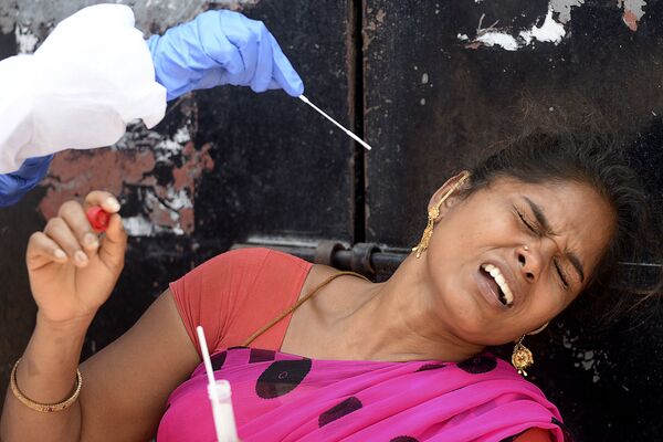 Медработник берет мазок у женщины для теста на коронавирус в жилом районе Ченнаи, Индия - Sputnik Армения