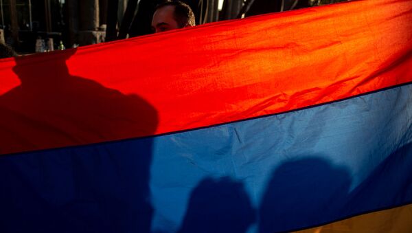 Национальный флаг Армении в руках участника акции в поддержку признания независимости Карабаха (13 октября 2020). Еревaн - Sputnik Армения