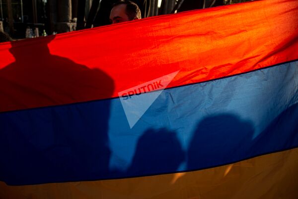 Национальный флаг Армении в руках участника акции в поддержку признания независимости Карабаха (13 октября 2020). Еревaн - Sputnik Армения