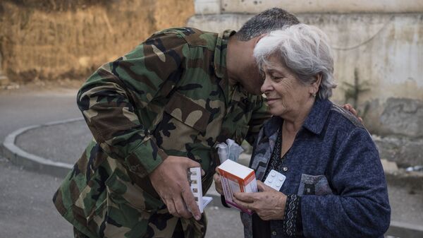 Волонтер в форме передает лекарства пожилой женщине в Степанакерте (16 октября 2020). Карабах - Sputnik Армения