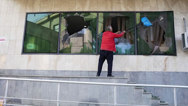 Мужчина убирает разбитые стекла на месте удара по зданию родильного дома в Степанакерте вследствие обстрелов города ВС Азербайджана (28 октября 2020). Карабах - Sputnik Армения