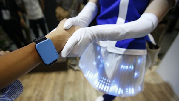 Посетитель с синим браслетом пожимает руку демонстратору Panasonic во время ежегодной выставки передовых технологий CEATEC Japan (6 октября 2016). Япония - Sputnik Армения