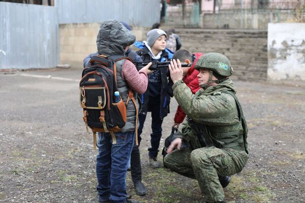 Мальчишки рассматривают оружие миротворца во дворе школы в Степанакерте - Sputnik Армения