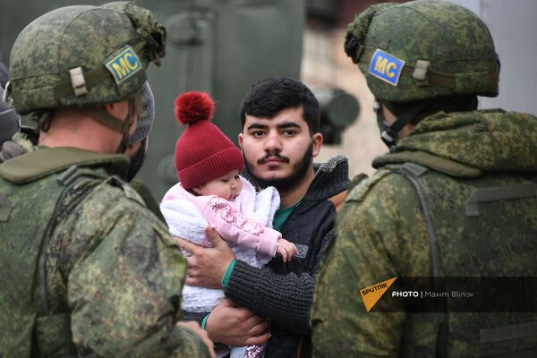 Мужчина с ребенком стоит рядом с российскими миротворцами, доставивишие воду в населённые пункты Аскеранского района - Sputnik Армения