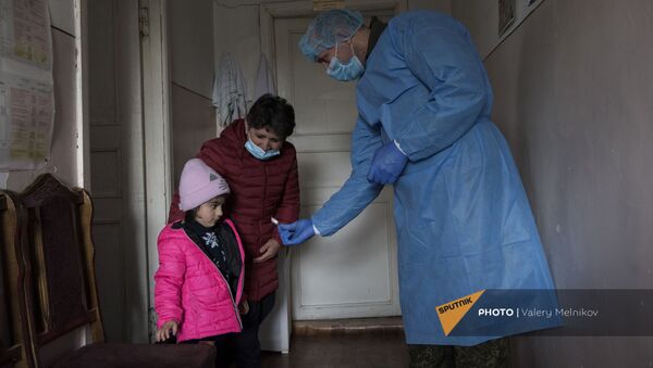 Врач выездной бригады российского медицинского миротворческого отряда угощает конфетой юную пациентку после приема в селе Айгестан Аскеранского района - Sputnik Արմենիա