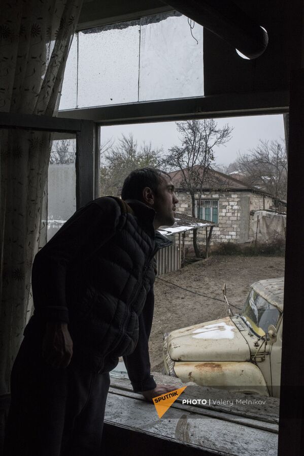 Мужчина смотрит из окна своего дома в селе Тагавард Мартунинского района (11 декабря 2020). Карабах - Sputnik Армения