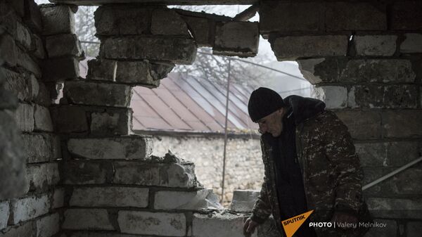 Мужчина в поврежденном от обстрелов доме в селе Тагавард Мартунинского района (11 декабря 2020). Карабах - Sputnik Армения