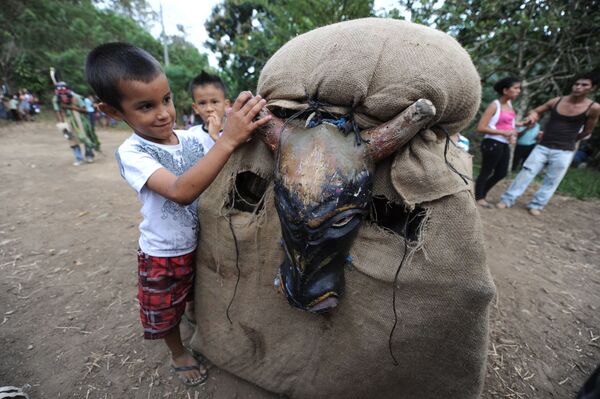 Мальчик играет с участником фестиваля Feast of the Devils в костюме быка в Коста-Рике  - Sputnik Армения