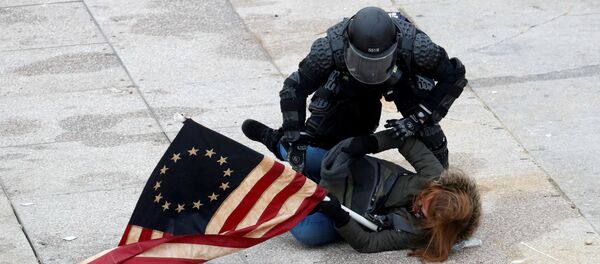 Офицер полиции задерживает участника акции протеста сторонников действующего президента США Дональда Трампа у здания Конгресса (7 декабря 2021). Вашингтон - Sputnik Армения