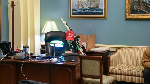 Сторонник президента США Дональда Трампа сидит в кабинете спикера Палаты представителей Нэнси Пелоси во время акции протеста в Капитолии (6 декабря 2021). Вашингтон - Sputnik Армения