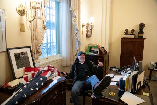 Cторонник президента США Дональда Трампа, Ричард Барнетт, сидит в кабинете спикера палаты представителей США Нэнси Пелоси во время акции протеста в Капитолии (6 декабря 2021). Вашингтон - Sputnik Армения