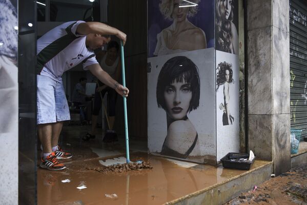 Мужчина убирает грязь с территории магазина, оставшуюся после наводнения в бразильском Белу-Оризонти - Sputnik Армения