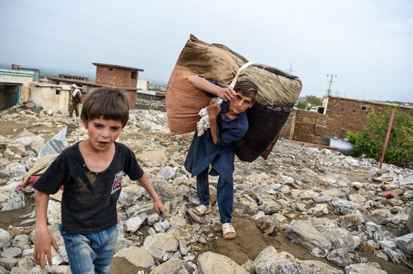 Молодые люди спасают остатки вещей из развалин домов после внезапного наводнения в Чарикаре, провинция Парван, Афганистан - Sputnik Армения