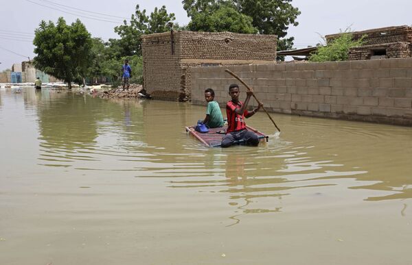 Подростки плывут на плоту по затопленной в результате наводнения улице в городе Салмания, Судан - Sputnik Армения