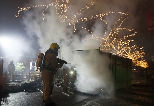 Пожарный тушит контейнер, подожженый во время протестов против общенационального комендантского часа в Роттердаме (25 января 2021). Нидерланды - Sputnik Армения