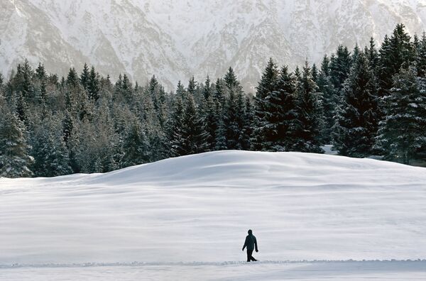 Мужчина идет сквозь снег недалеко от Гармиш-Партенкирхена, Германия - Sputnik Армения