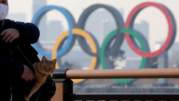Мужчина с котом в сумке на фоне олимпийских колец в Токио - Sputnik Армения