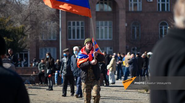 Оппозиционер с флагами на плечах и в руках перед началом акции оппозиции на перекрытом проспекте Баграмяна (26 февраля 2021). Еревaн - Sputnik Արմենիա