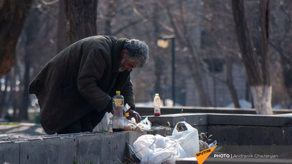 Бездомный мужчина обедает в городском парке - Sputnik Армения