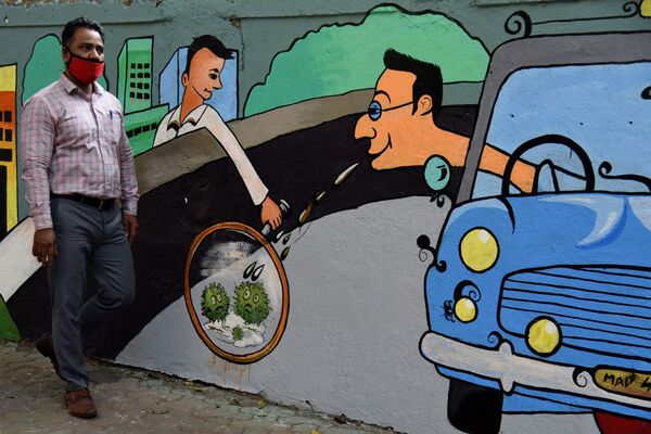 Пешеход идет мимо стены с граффити на тему коронавируса в Мумбае, Индия - Sputnik Армения
