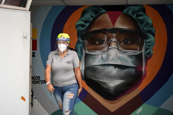 Медицинский работник в защитной маске у граффити в Каракасе - Sputnik Армения