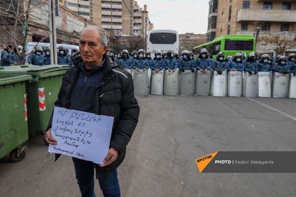Мужчина держит плакат с надписью Я рядом со своей армией, чтоб защитить ее от шакалов. Офицер в запасе на фоне полицейского кордона со щитами (10 марта 2021). Еревaн  - Sputnik Армения
