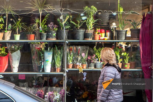 Девушка проходит мимо витрины цветочного магазина на улице Касьяна (8 марта 2021). Еревaн - Sputnik Армения