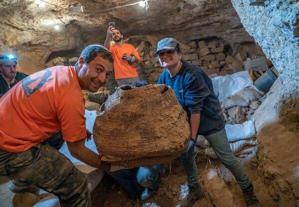 Израильские археологи с древней корзиной, найденной в пещере Мурабаат в Иудейской пустыне недалеко от Мертвого моря - Sputnik Армения