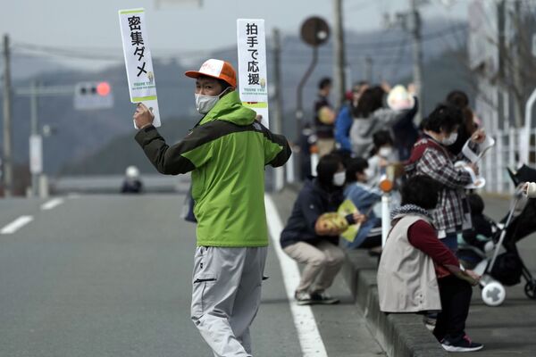 Мужчина с табличками во время эстафеты Олимпийского огня в Токио-2020 в префектуре Фукусима, Япония - Sputnik Армения