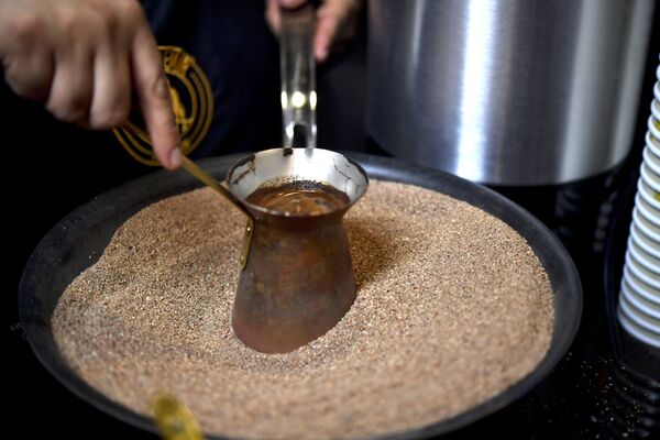 Мексиканский бариста готовит фирменный турецкий кофе в медном горшочке на горячем песке, Мехико - Sputnik Армения