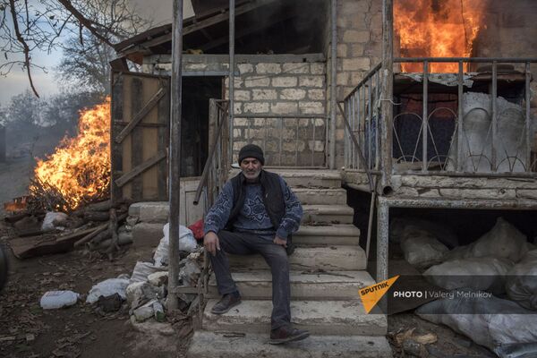 Местный житель сидит у горящего дома в поселке Карегах (25 ноября 2020). Карабах - Sputnik Армения