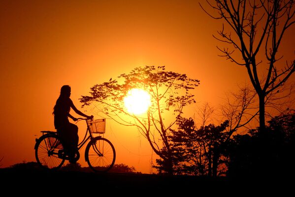 Индийская девушка катается на велосипеде во время заката в деревне Джойпур - Sputnik Армения