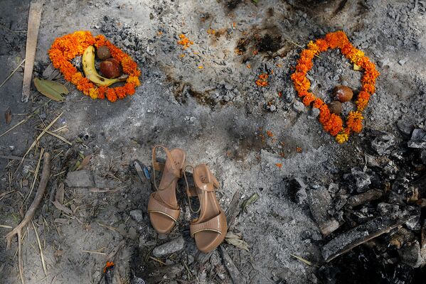 Цветочные гирлянды, фрукты и обувь женщины на месте кремации в Нью-Дели, Индия - Sputnik Армения