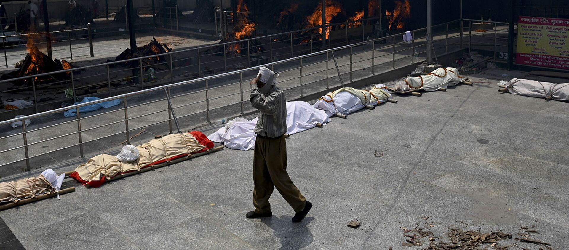 Мужчина проходит мимо тел жертв коронавируса Covid-19, выстроенных в очередь перед кремацией в Нью-Дели (28 апреля 2021). Индия - Sputnik Արմենիա, 1920, 02.05.2021