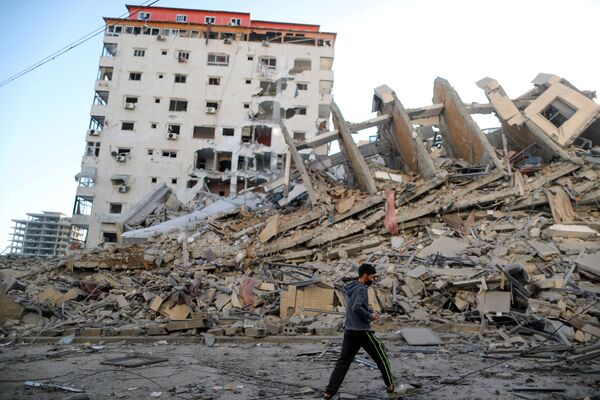 Палестинский мальчик проходит мимо руин здания, разрушенного в результате израильских авиаударов на фоне вспышки израильско-палестинского конфликта, Газа - Sputnik Армения