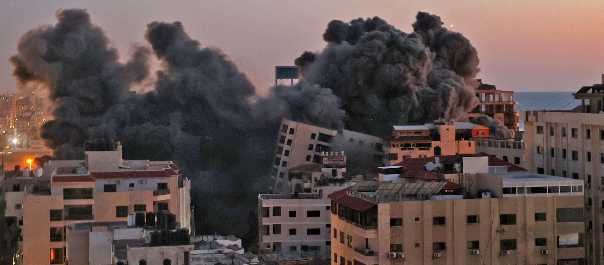 Пожарные тушат горящие многоквартирные дома после израильских авиаударов в городе Газа - Sputnik Արմենիա, 1920, 17.05.2021