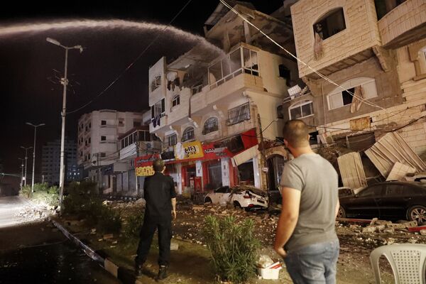 Пожарные тушат горящие жилые дома после того, как они пострадали от израильских авиаударов, в городе Газа - Sputnik Армения