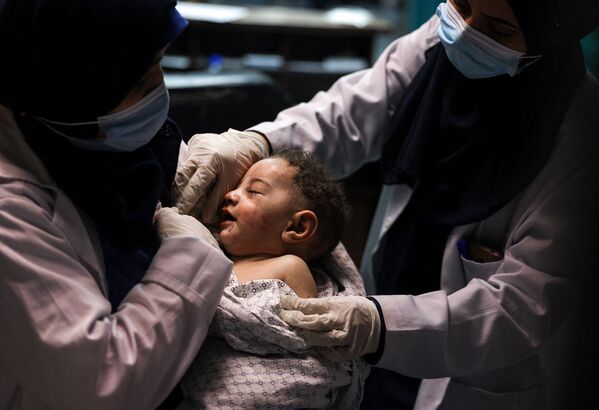 Медсестра держит ребенка, которого вытащили живым из-под завалов, в то время как семь других членов семьи погибли в больнице Аль-Шифа после израильского удара по лагерю беженцев аш-Шати (15 мая 2021). Газа  - Sputnik Армения