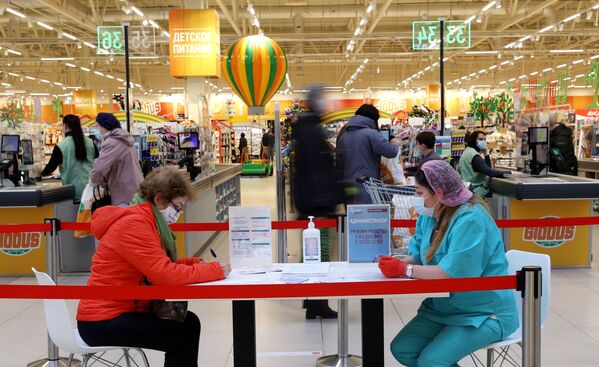 Женщина заполняет документы перед вакцинацией от COVID-19 российской вакциной Спутник V (Гам-КОВИД-Вак) в гипермаркете Глобус в Москве - Sputnik Армения