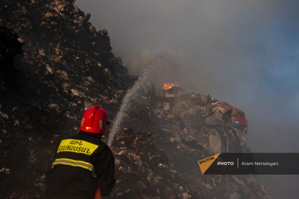 Сотрудник МЧС тушит пожар на нубарашенской мусорной свалке - Sputnik Армения
