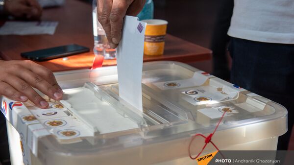 Избиратель закидывает конверт с бюллетенем в урну  - Sputnik Армения
