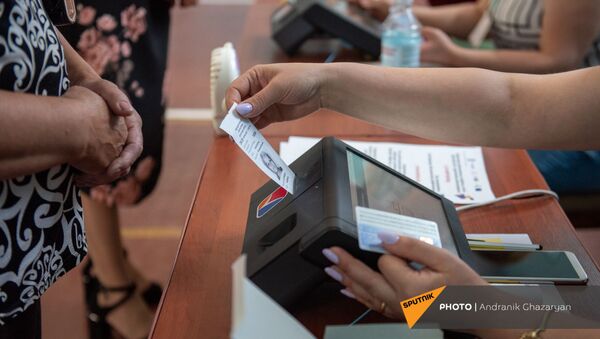 Сотрудник избирательной комиссии проверяет личность избирателя в избирательном участке 29/29 (20 июня 2021). Ариндж - Sputnik Армения