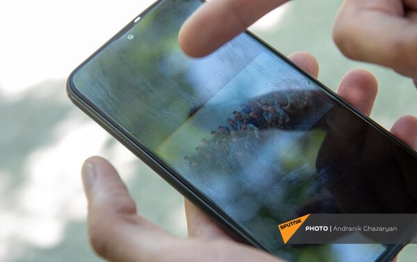 Получивший ранение в карабахской войне капитан Тигран Мнацаканян показывает фотографии на смартфоне - Sputnik Армения