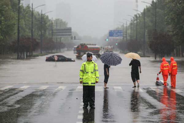 Офицер полиции на переходе затопленной улицы после проливных дождей в Чжэнчжоу в центральной провинции Китая Хэнань - Sputnik Армения