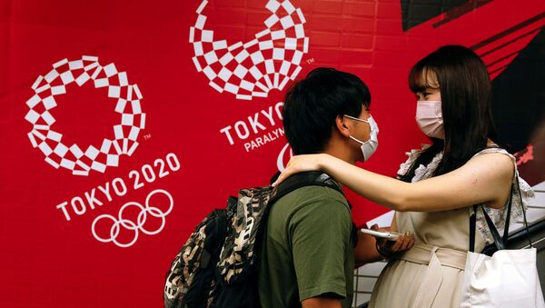 Пара на эскалаторе на фоне олимпийских баннеров на станции Китасандо в Токио - Sputnik Армения