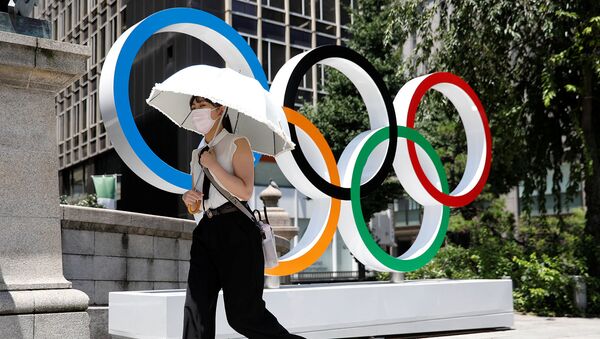 Женщина проходит мимо Олимпийских колец в Токио - Sputnik Արմենիա